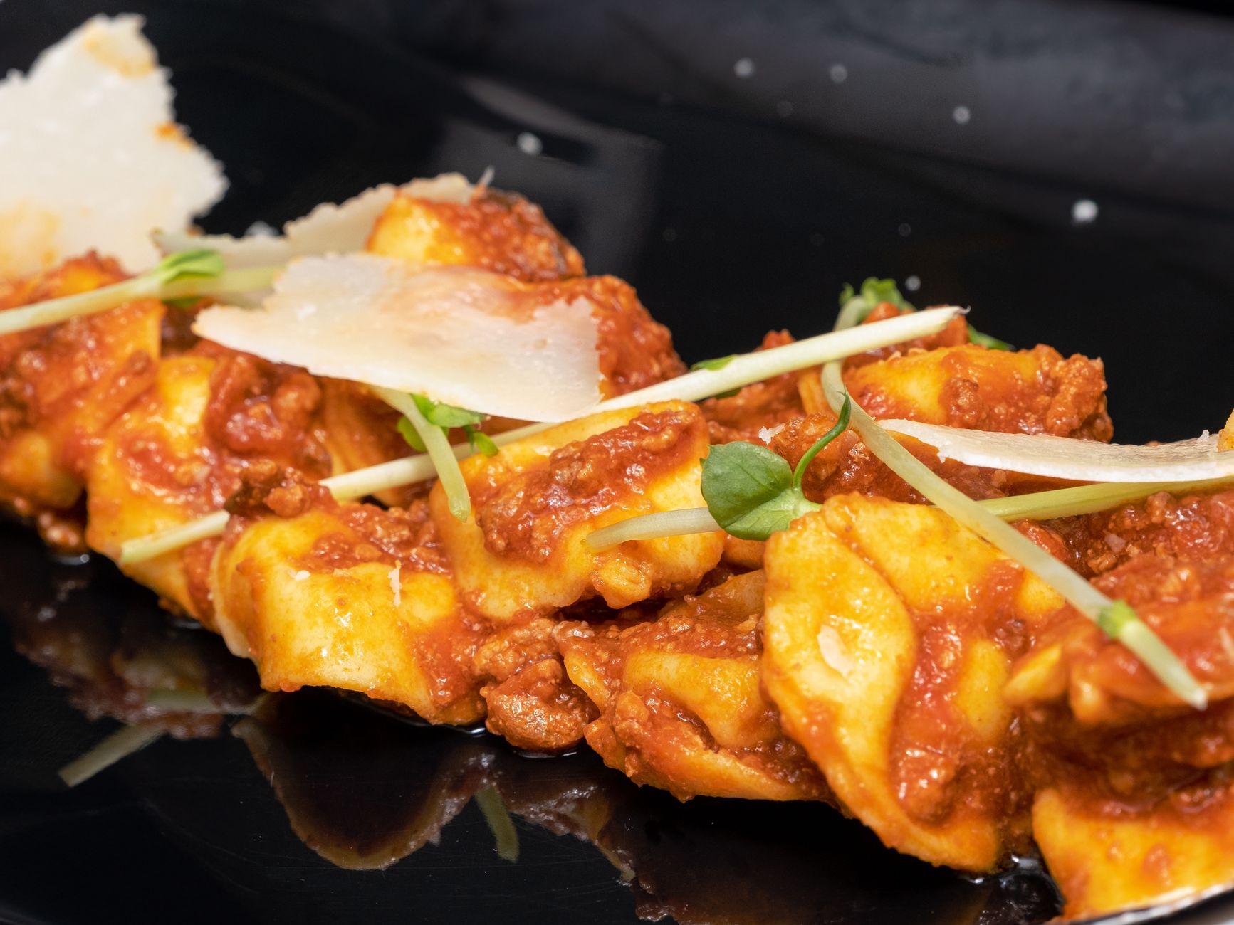 Ravioli mit Tomatensugo und Käse auf dunklem Teller